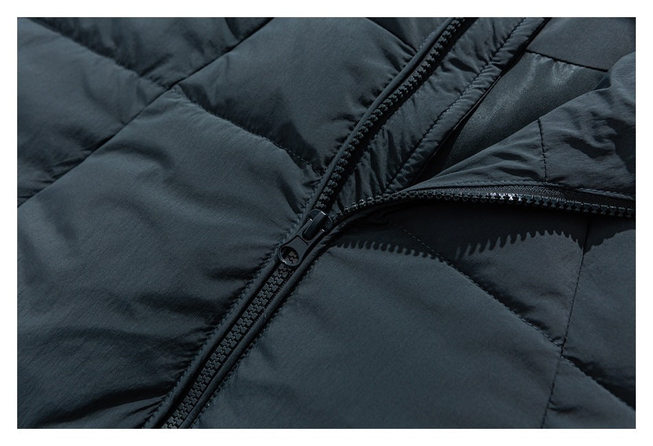 Close-up of the dark blue-gray padded jacket's black front zipper and stitched panels.