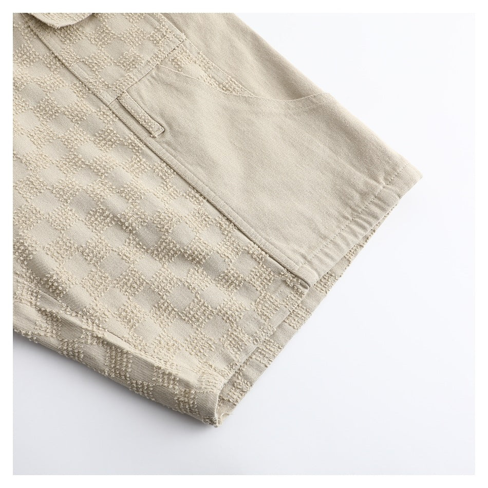 Close-up of a beige trouser leg showing the textured check pattern and plain hem area.