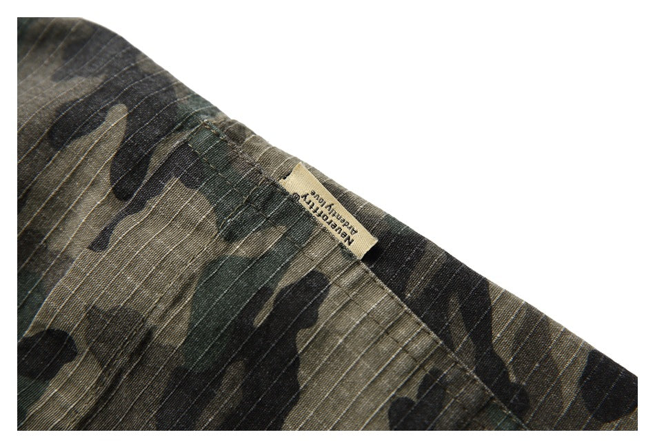 Close-up of a tan clothing label sewn onto dark green, brown, and black camouflage fabric.