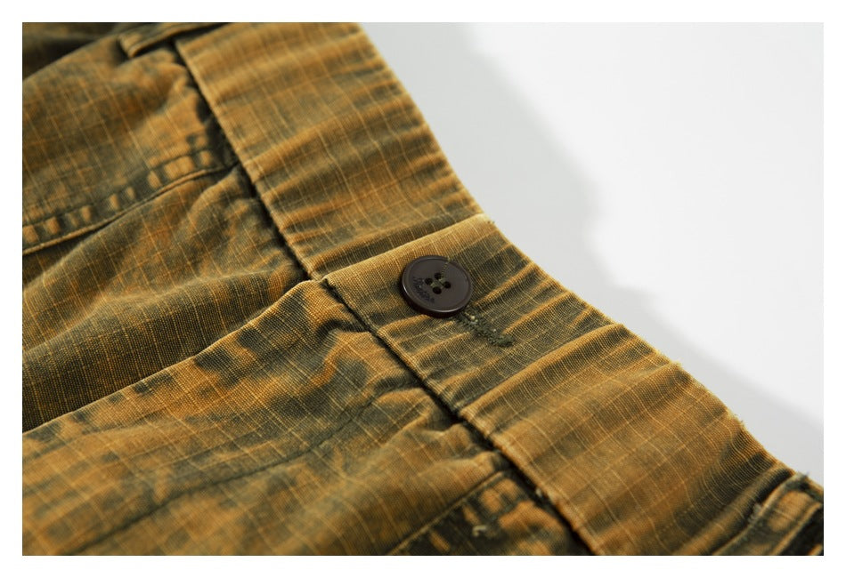 Close-up of the pants' waistband, belt loop, and dark button on mottled ochre-brown fabric.