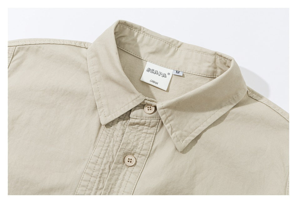 Close-up of a light beige short-sleeve shirt collar, buttons, and stitched placket.