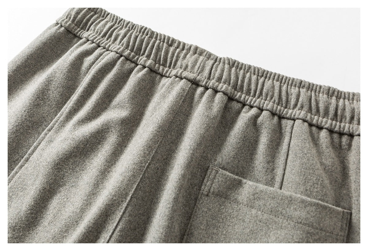 Close-up of the back of light gray pants, showing the elastic waistband and a patch pocket.