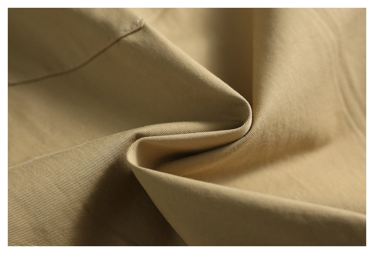Close-up of tan twill fabric draped in soft folds, showing its fine diagonal weave.