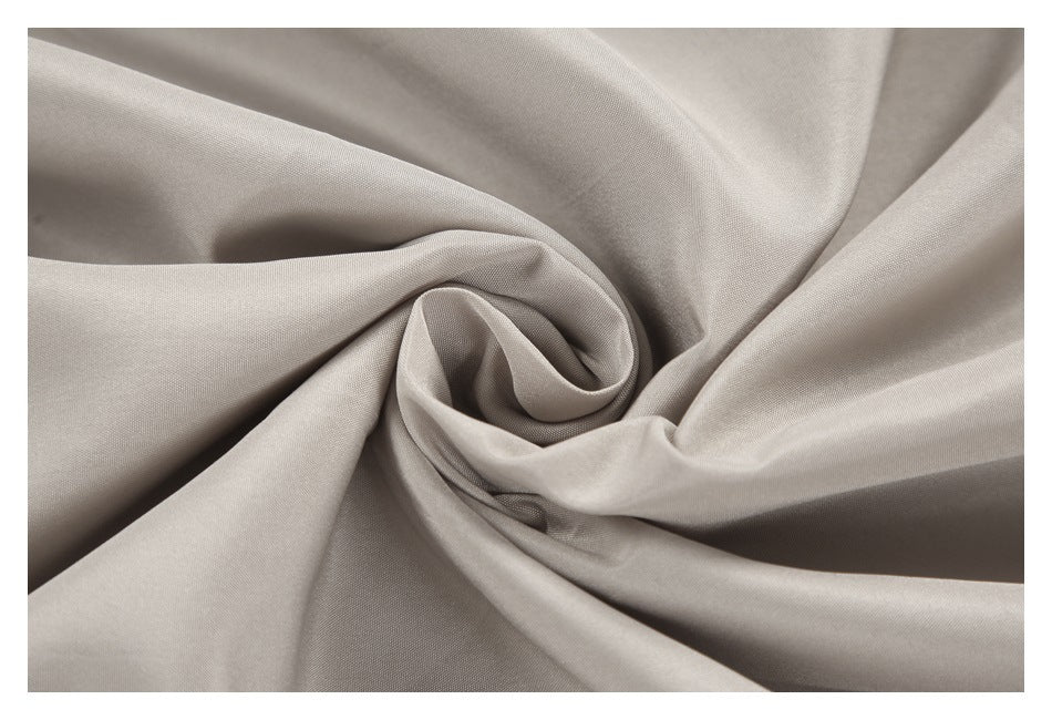 Close-up of light taupe fabric arranged in a spiral to show its surface and drape.