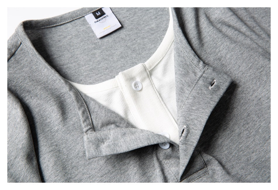 Close-up of a gray shirt's white button-front placket and inner neck label.