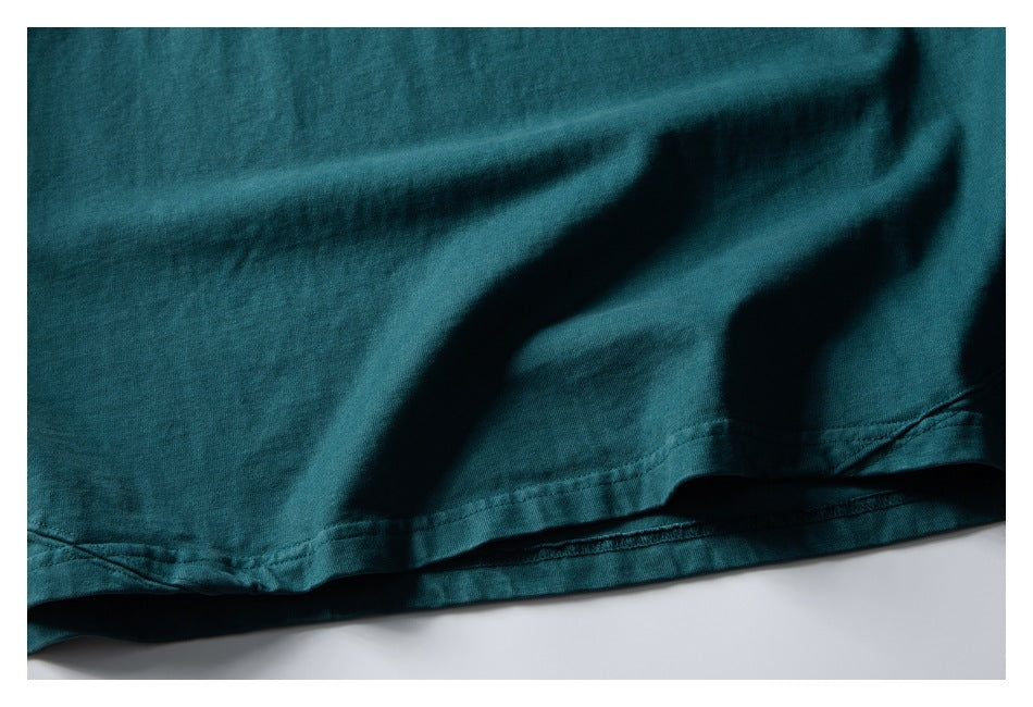 Close-up of the dark teal garment's double-stitched bottom hem.