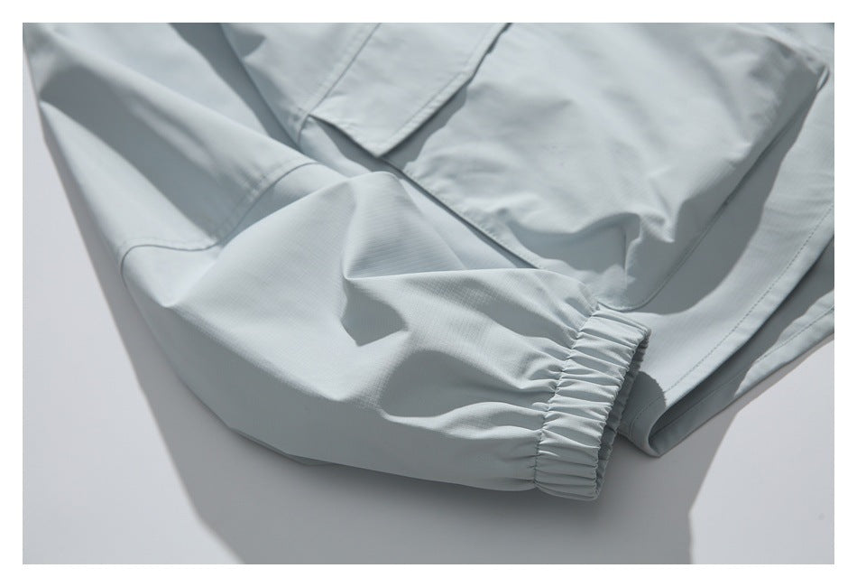 Close-up of a pale gray jacket sleeve with a gathered elastic cuff and part of a front pocket.