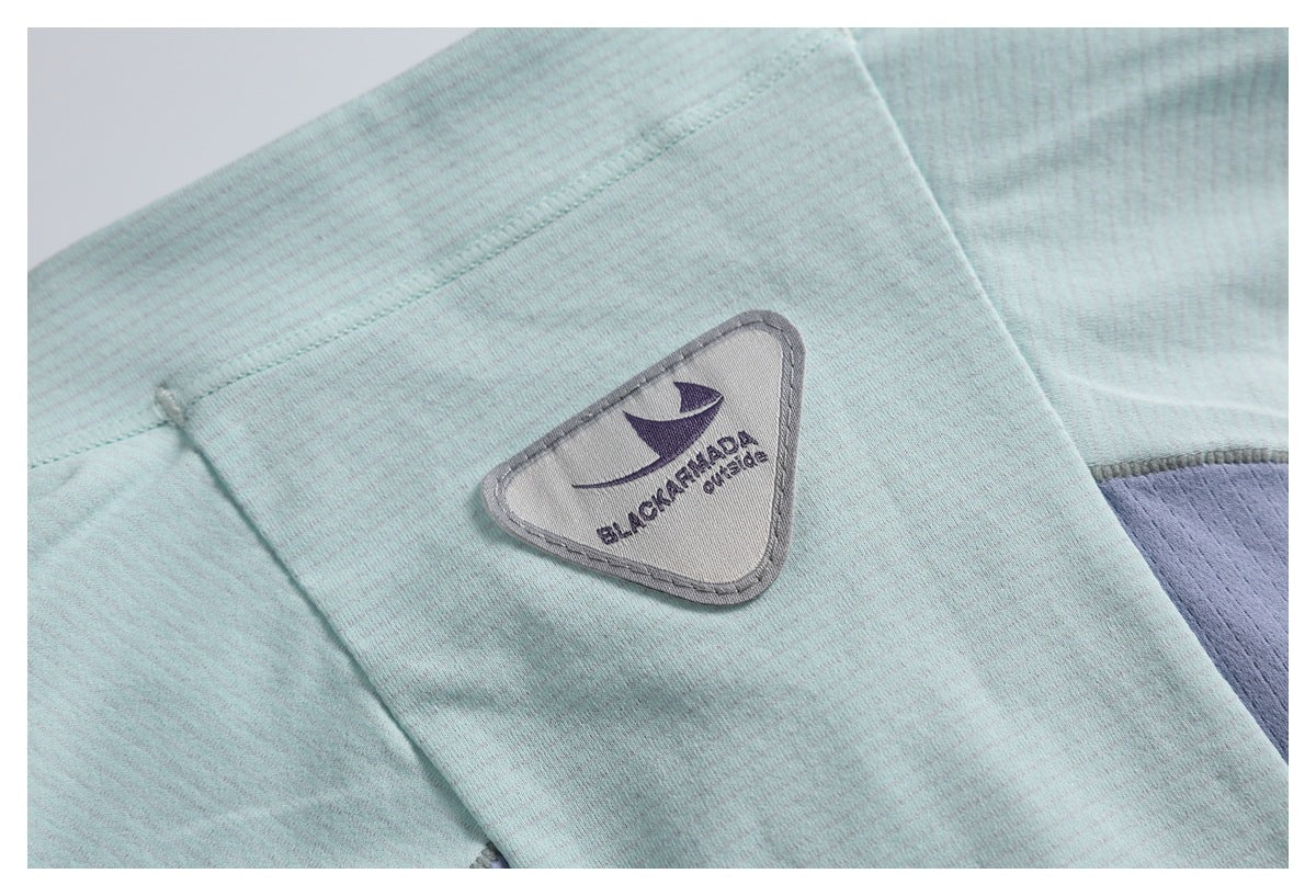 Close-up of pale aqua striped fabric with a triangular embroidered brand patch.