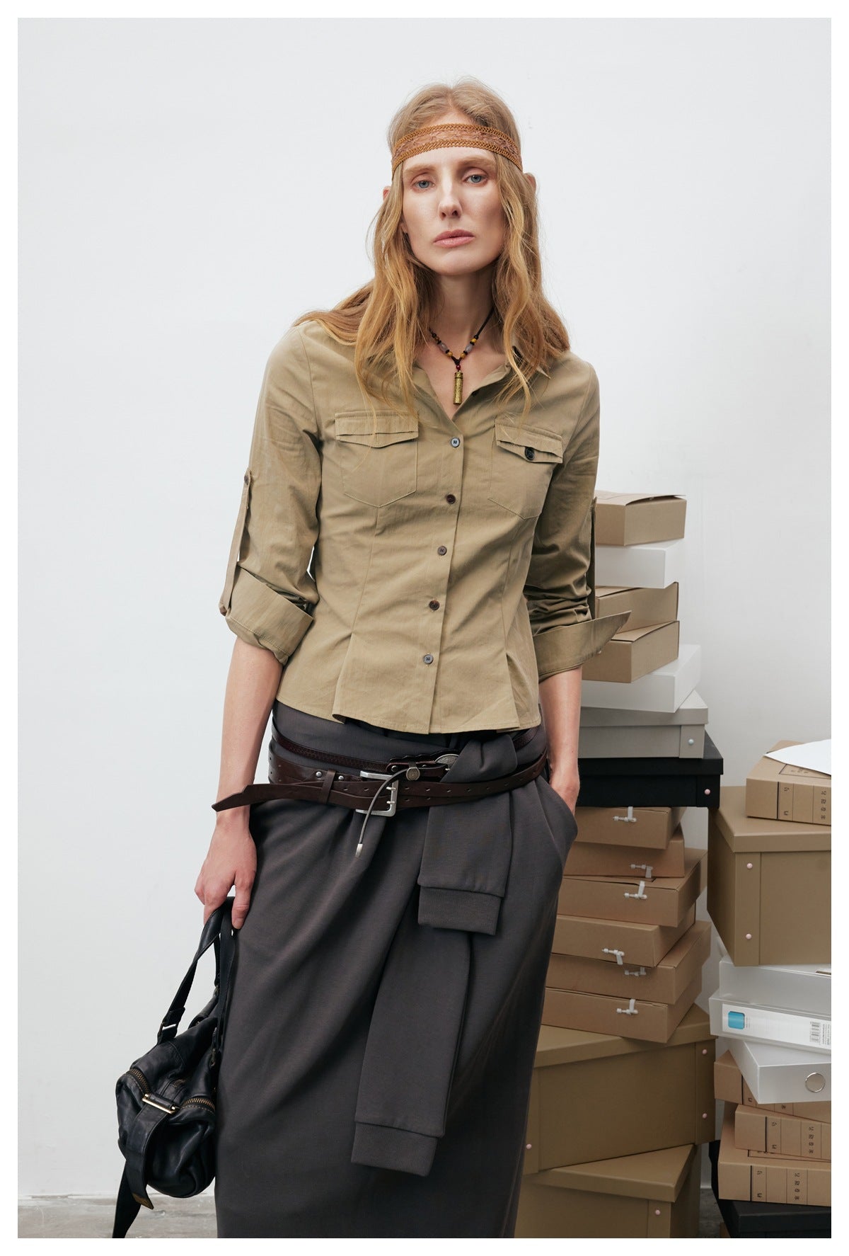 Close-up of model in khaki shirt jacket with chest flap pockets, rolled sleeves and fitted waist, with a headband
