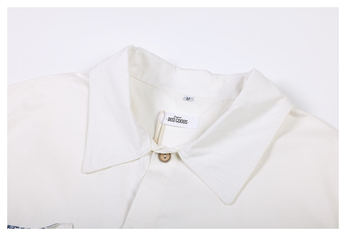 Close-up of the ivory shirt's wide collar, tan button, and neck label.