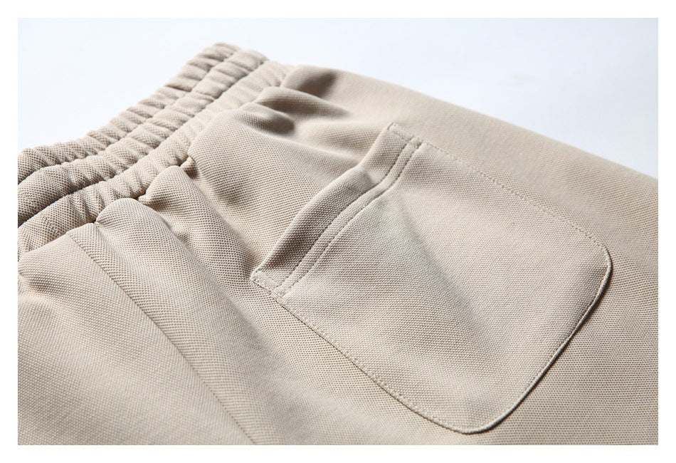 Angled close-up of a light beige garment's elastic waistband and patch pocket.