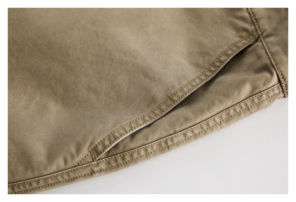 Close-up of tan trouser fabric, curved pocket stitching, and a finished edge.