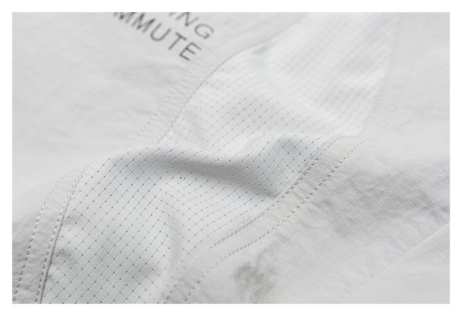 Close-up of light gray fabric with curved seams, fine grid stitching, and partial gray lettering.