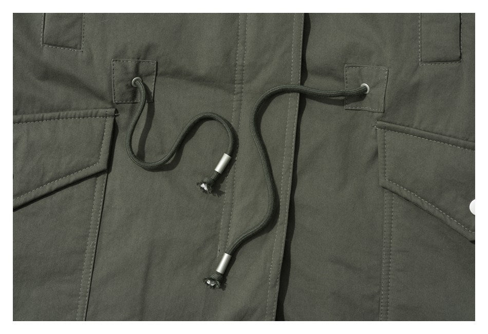 Close-up of dark olive garment panels with stitched tabs and long adjustable drawcords with metal tips.