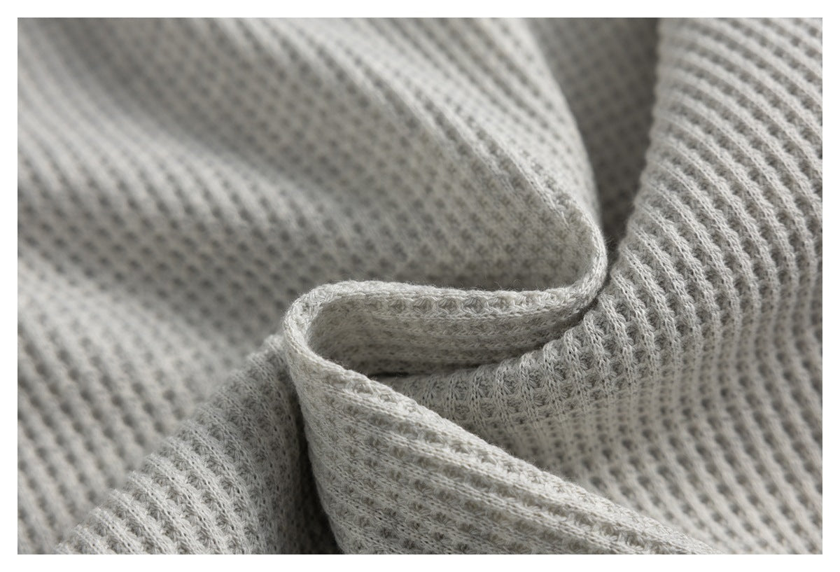 Close-up of light gray ribbed knit fabric folded to show its textured weave.
