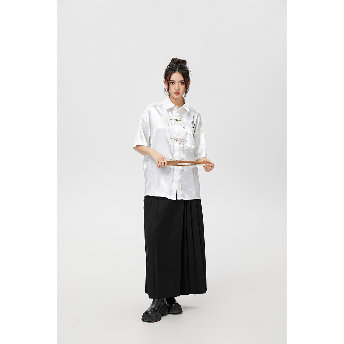 Model wearing a white short-sleeve knot-front shirt with subtle floral pattern and bamboo embroidery, paired with a black