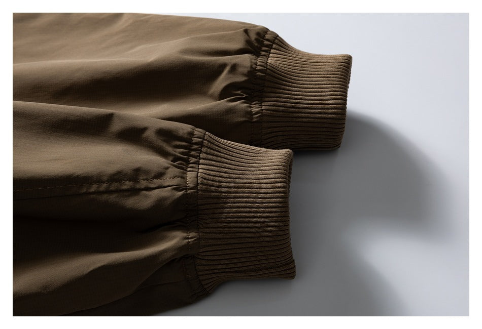 Close-up of two brown jacket sleeves ending in wide rib-knit cuffs.