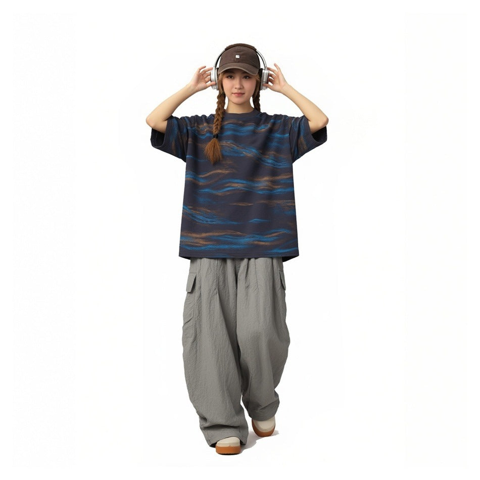 Model wearing a navy T-shirt with blue and brown wave stripes and loose gray cargo pants.