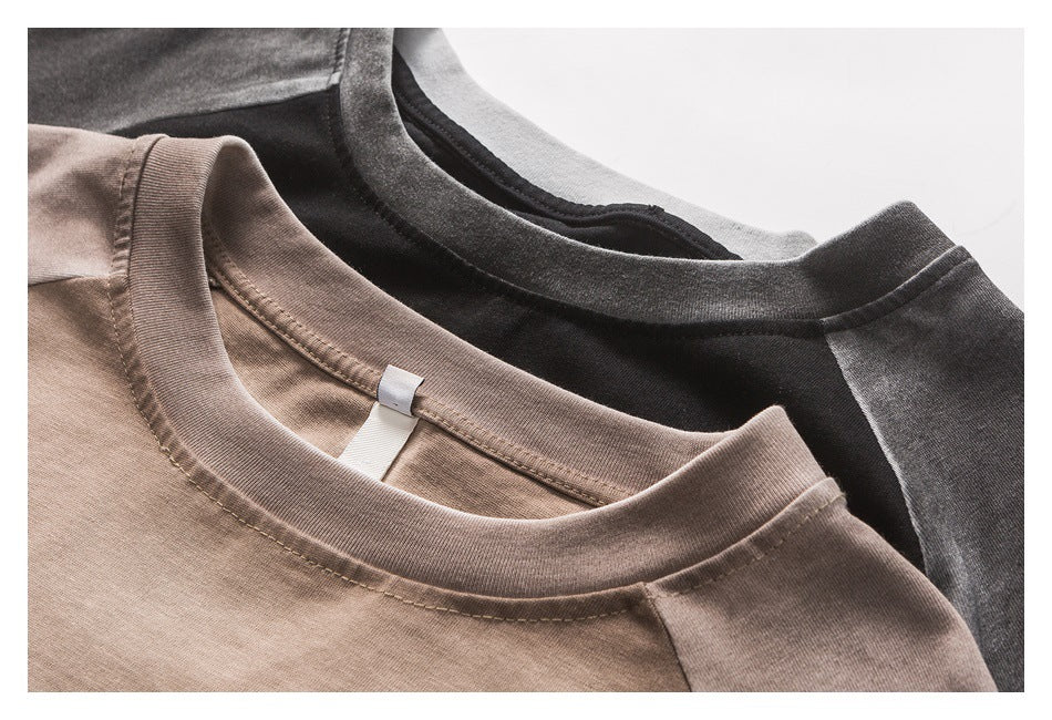 Close-up of taupe and charcoal raglan T-shirts showing their ribbed crew necklines and stitching.