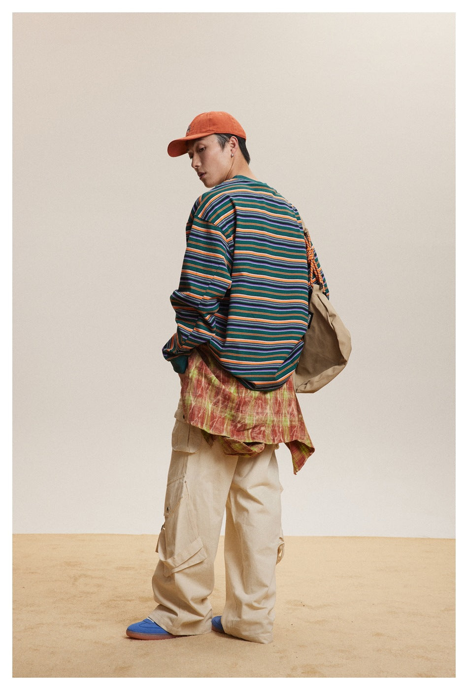Rear view of a model wearing a green long-sleeve shirt with orange, purple, and light-colored horizontal stripes.