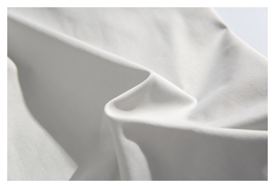 Close-up of smooth light gray fabric draped into soft folds.