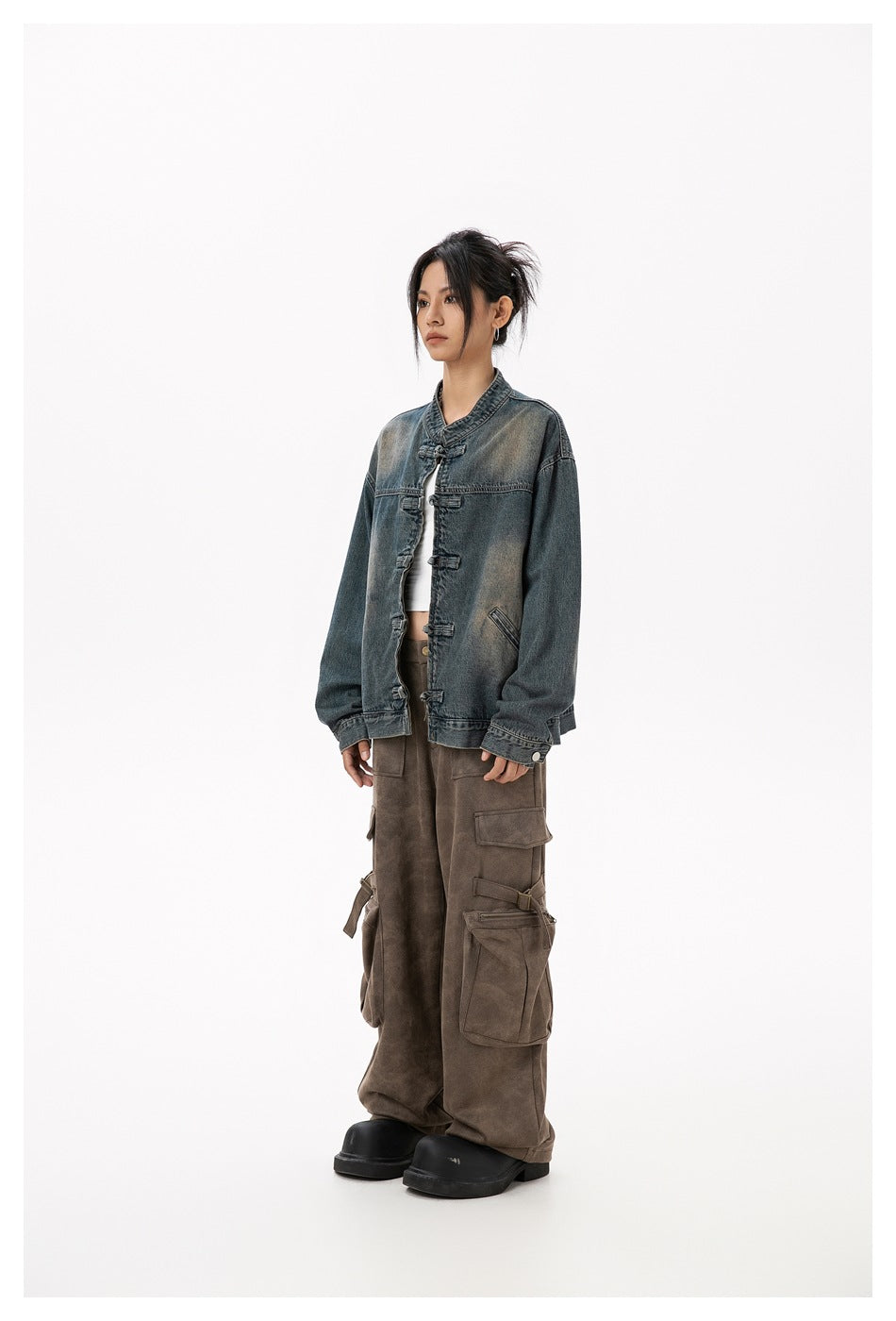 Model wearing the blue washed denim jacket open over a white top with brown cargo pants, side view