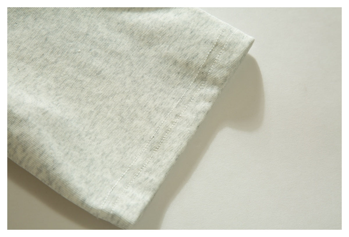 Close-up of the double-stitched hem on light gray heathered polo fabric.