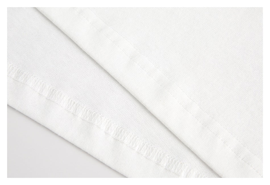 Close-up of white fabric showing a folded edge and overlock stitching.