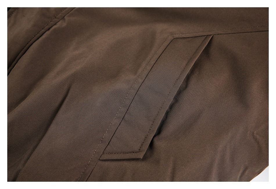 Close-up of a brown jacket's angled welt pocket and stitching.