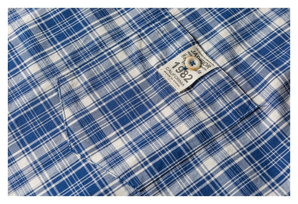 Close-up of the blue and white plaid shirt pocket, button, and sewn label.
