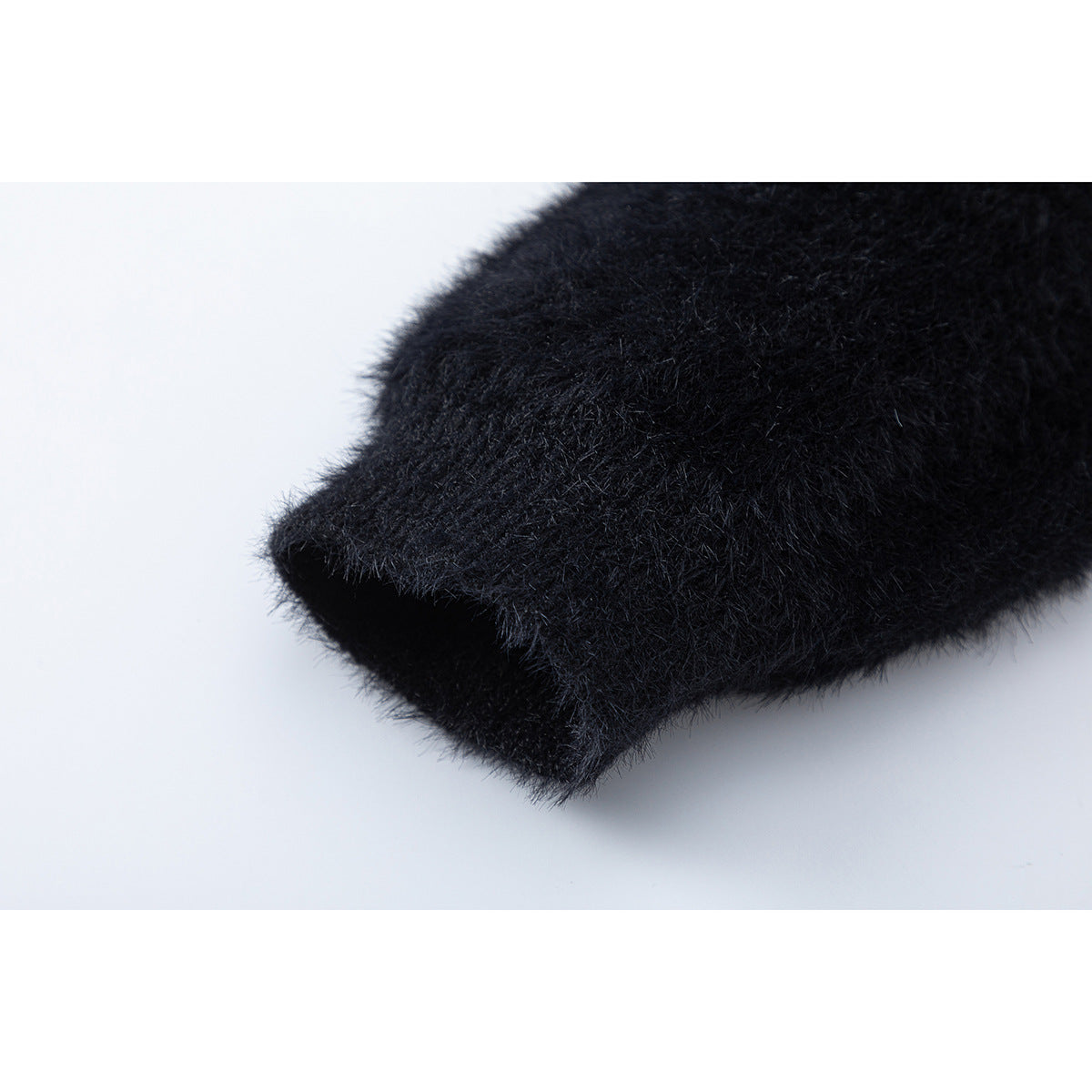 Close-up of the edge of a black fuzzy sweater sleeve and its thick cuff.
