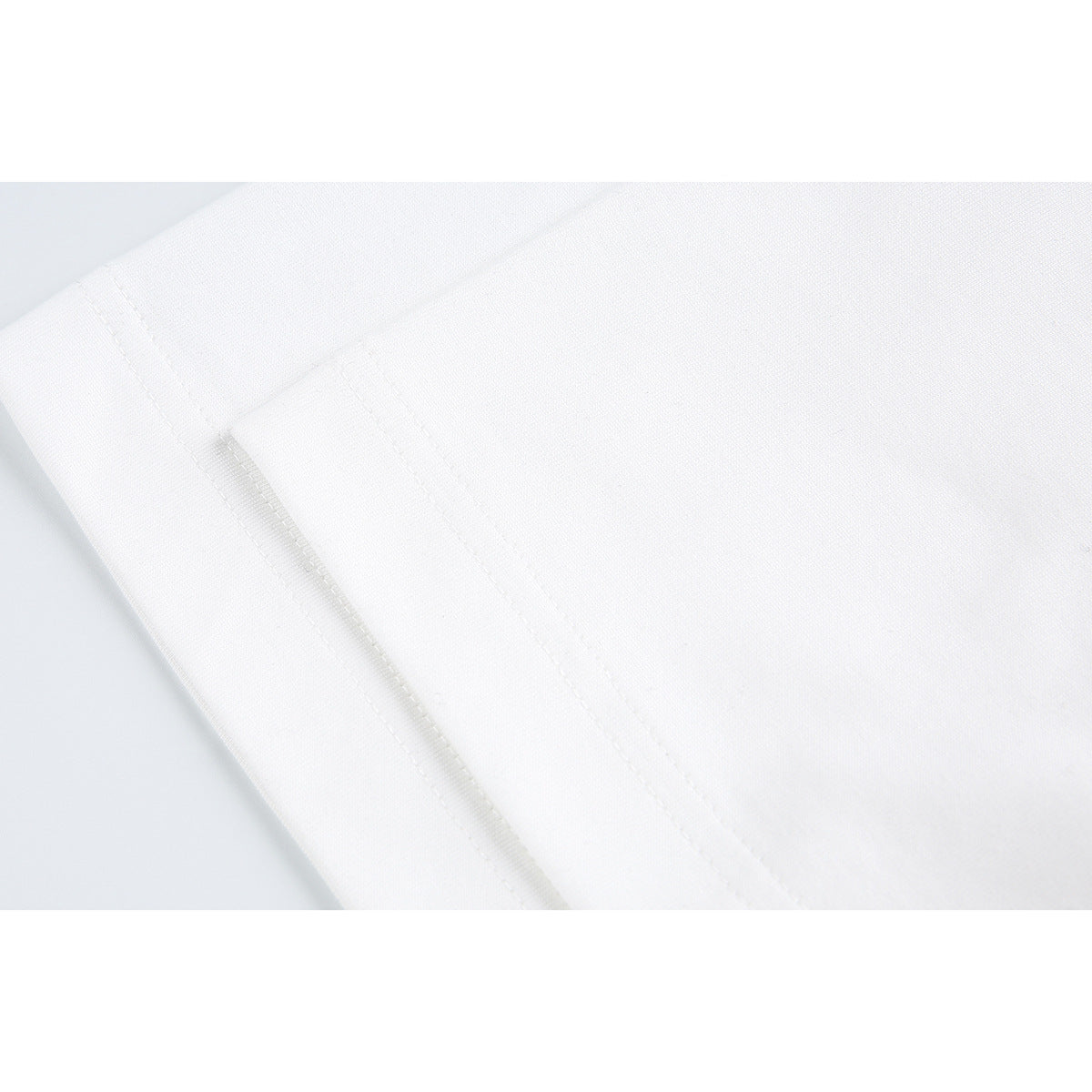 Close-up of white T-shirt fabric and stitched seam.