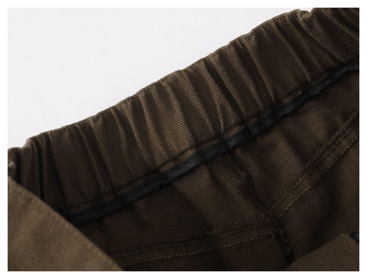 Inside view of brown trousers showing a gathered waistband, black trim and stitched seams.