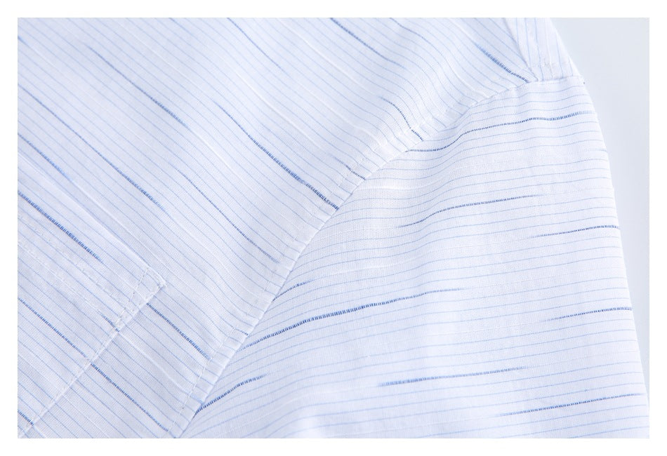 Close-up of a white shirt with fine blue stripes and a curved shoulder seam.