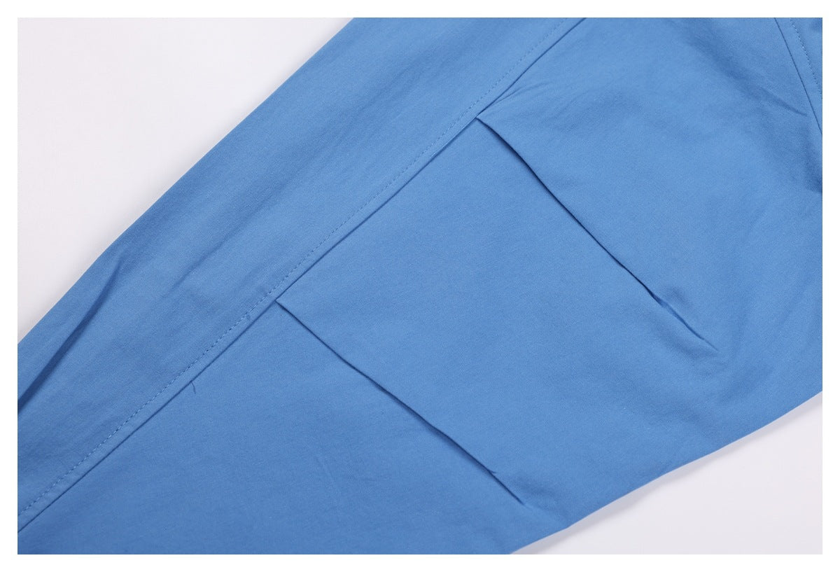Close-up of blue shirt fabric with a stitched seam and folded panel.