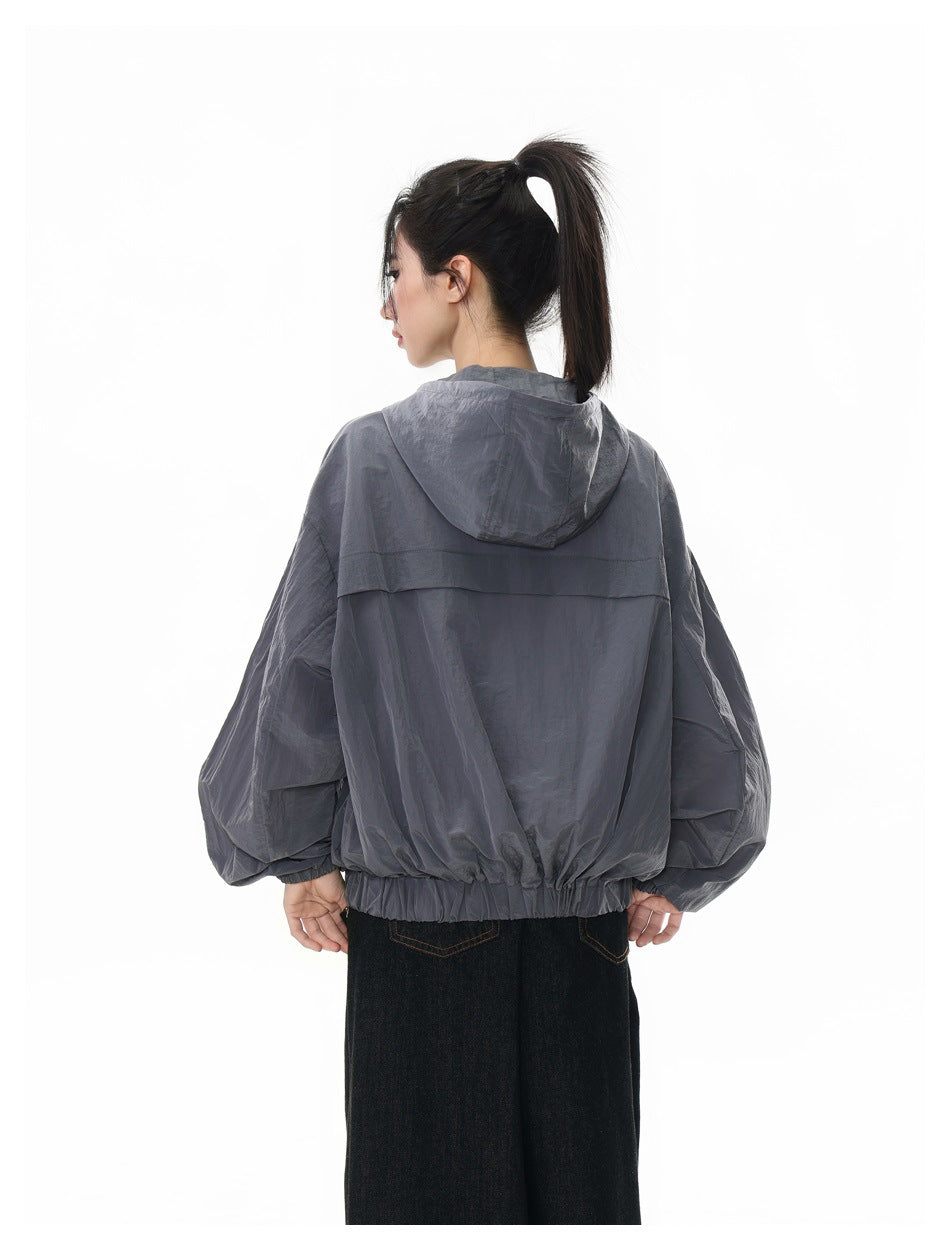 Model wearing a slate-gray hooded jacket, shown from the back with the hood down.