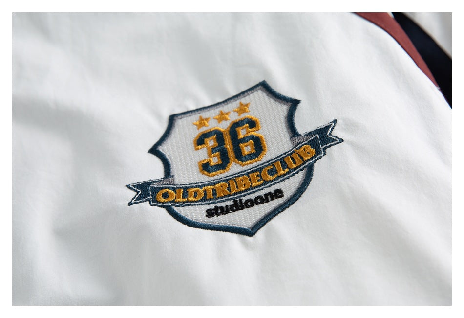Close-up of an embroidered navy, gold and white crest with the number 36 on a white jacket.
