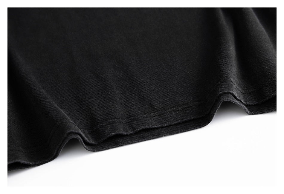 Close-up of the curved, stitched bottom hem of a black T-shirt.