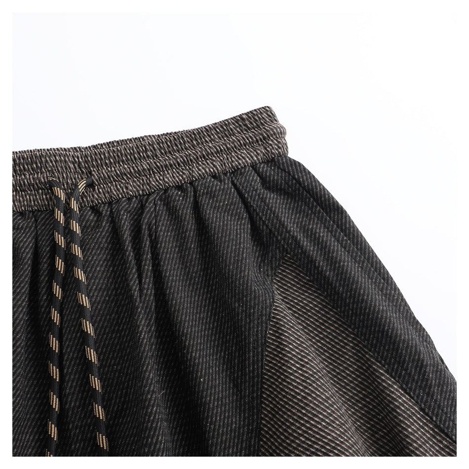 Close-up of the elastic waistband and angled pocket opening on dark striped pants.