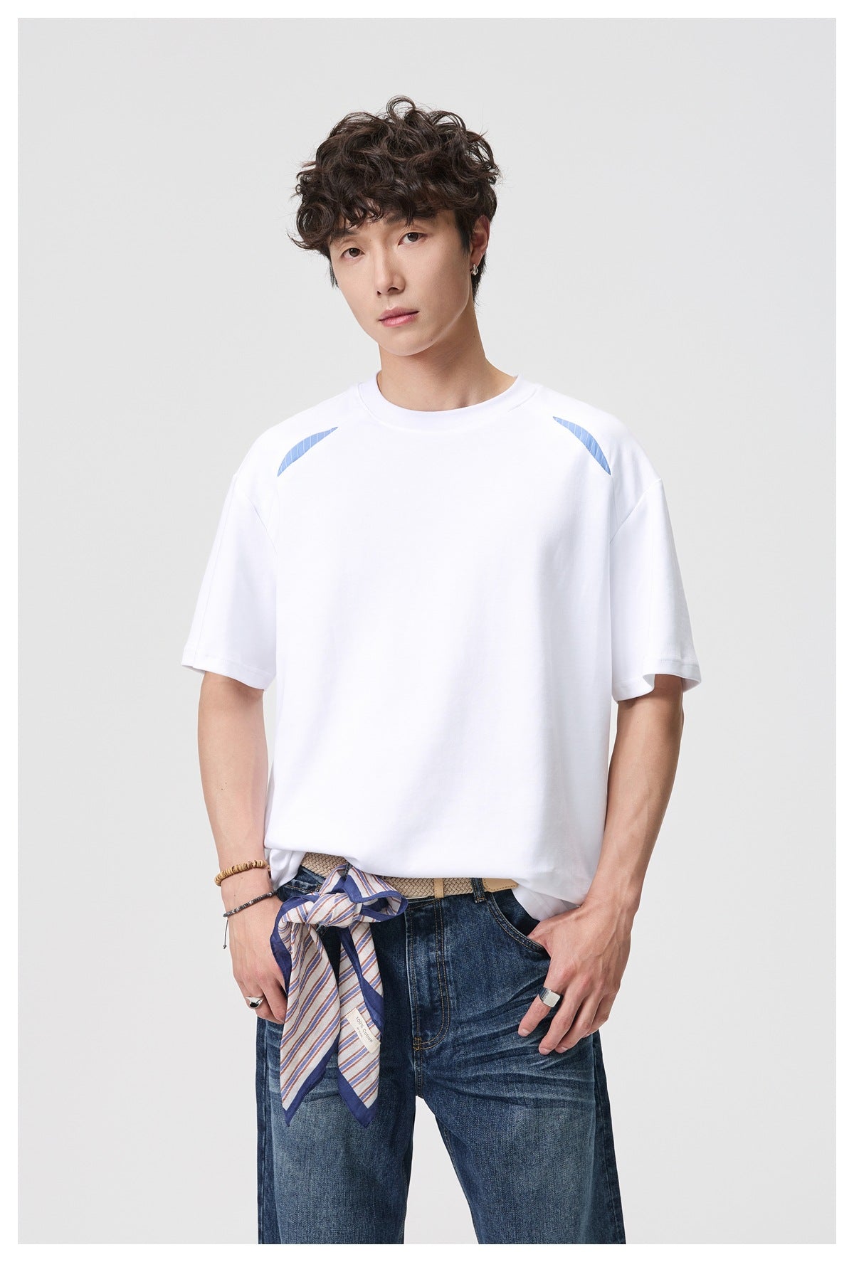 Model wearing a white oversized T-shirt with light-blue shoulder accents and blue jeans.