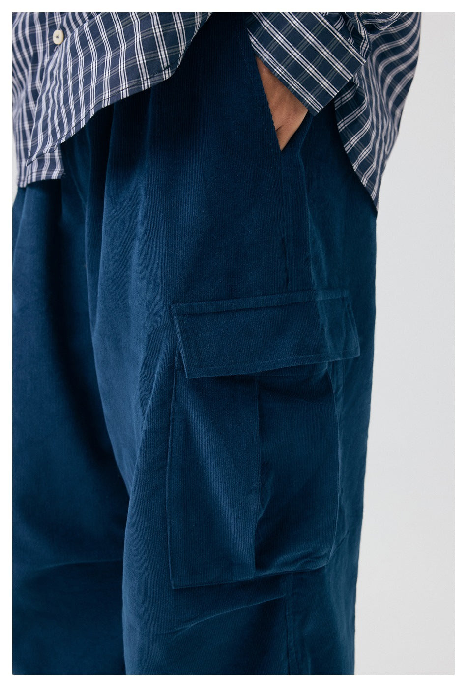 Close-up of the navy cargo pants’ layered side pockets, worn with a blue plaid shirt.