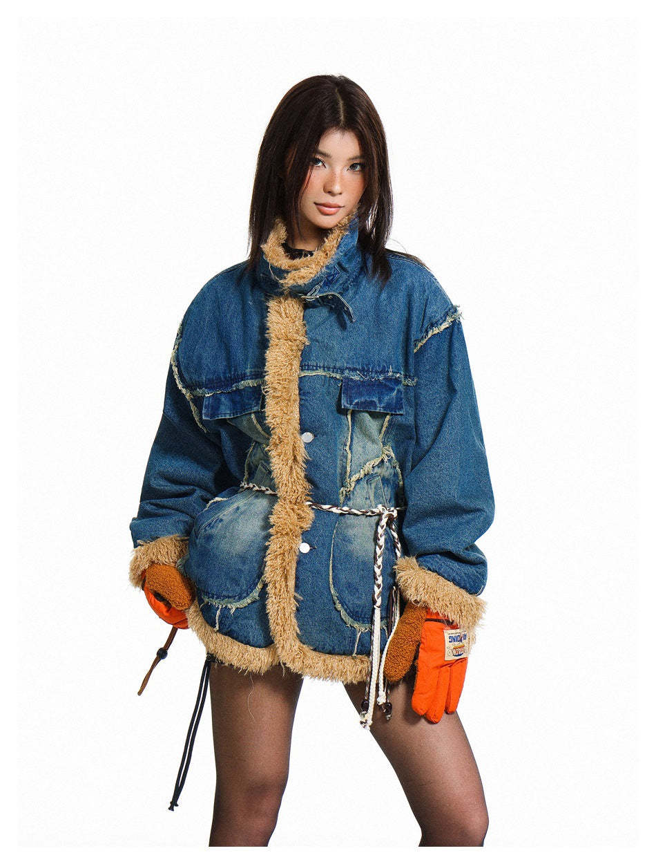 Model wearing a blue patchwork denim jacket with tan shaggy trim, a braided waist cord and orange gloves.