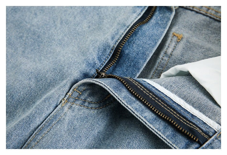Close-up of light blue jeans with the zipper fly open, showing the brass-tone zipper and interior stitching.