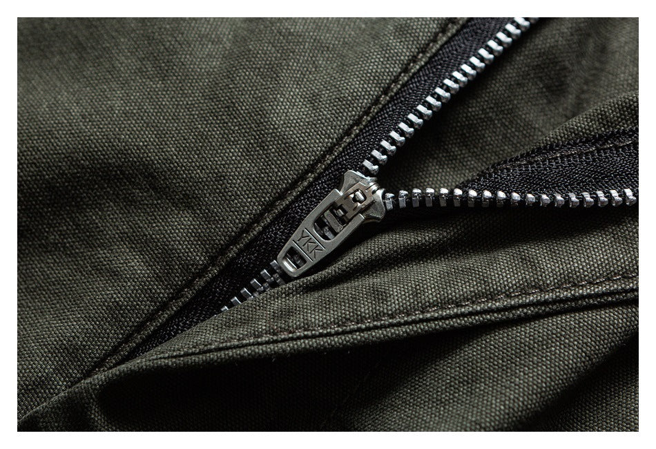 Macro view of a metal zipper on dark olive fabric.