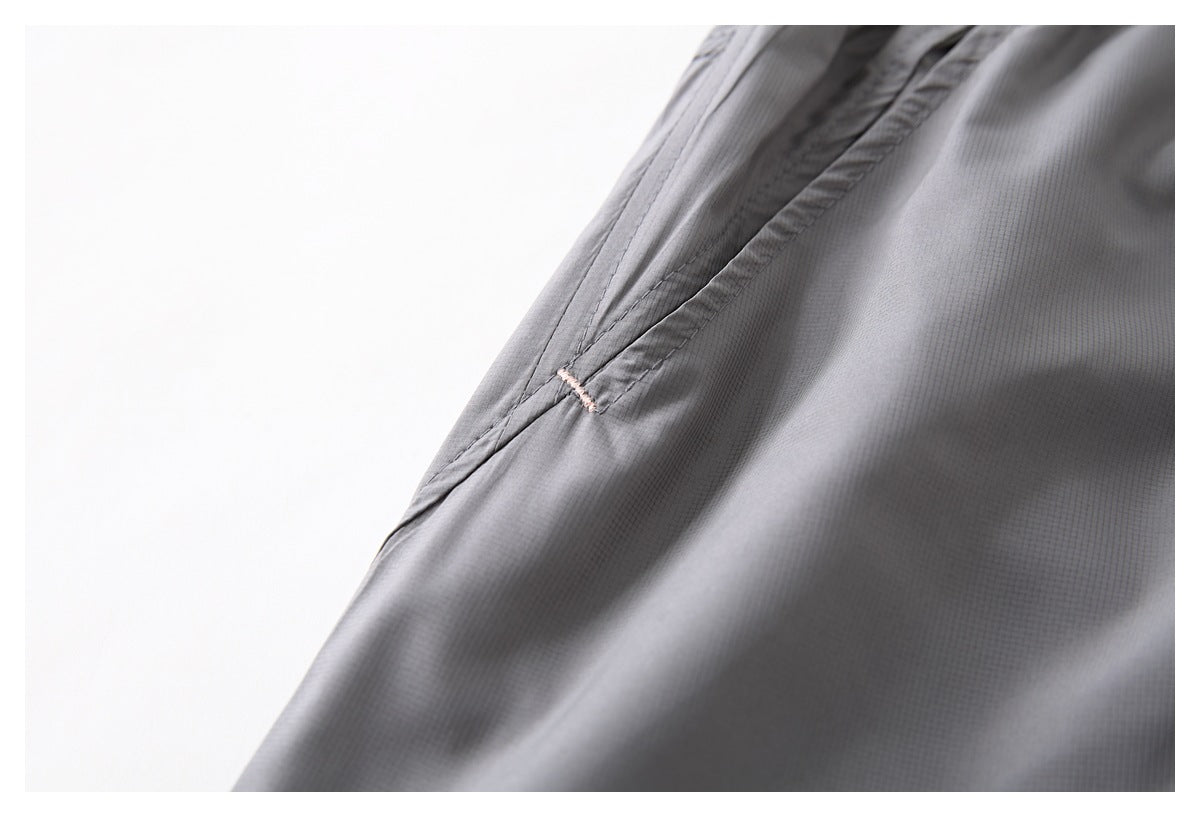Close-up of gray garment fabric and a seam finished with a small pale pink stitch.