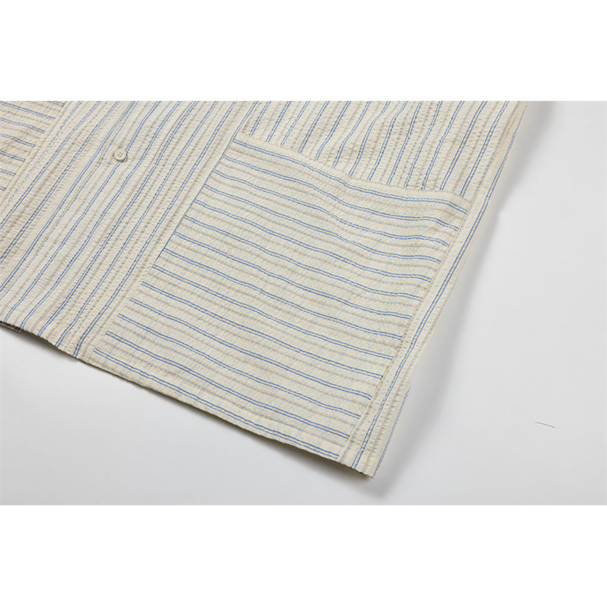 Close-up of a large chest pocket on a cream shirt with fine blue and tan stripes.