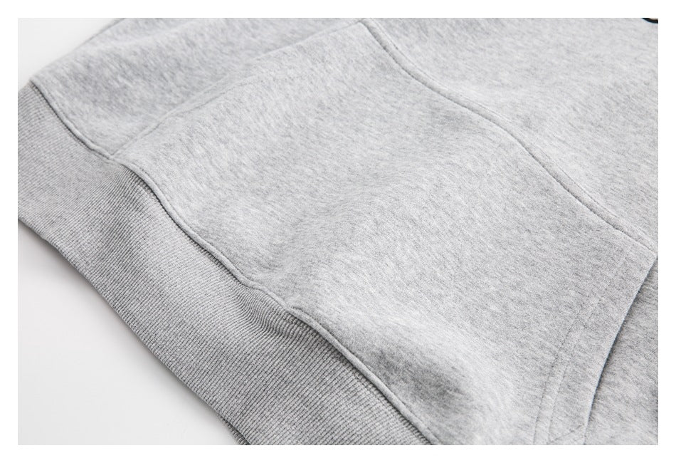 Close-up of a kangaroo pocket and ribbed waistband on a heather-gray sweatshirt.