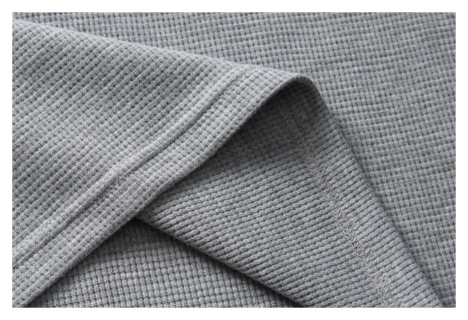 Close-up showing folded gray textured fabric and an overlocked seam.