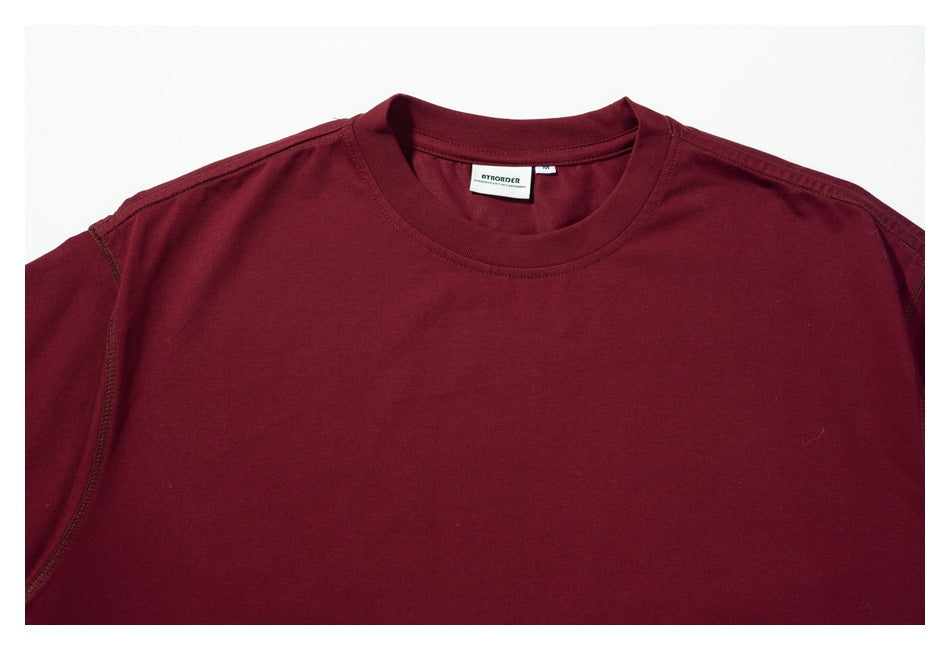 Close-up of the burgundy T-shirt’s crew neckline, shoulder seams, and inner brand label.