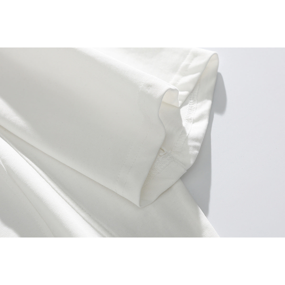 Close-up of the folded short sleeve and stitching on a white T-shirt.